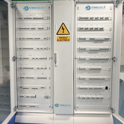 Armario de distribución modular Schneider Prismaset blanco, con puertas abiertas mostrando filas de dispositivos de protección y señal de "RIESGO ELÉCTRICO".